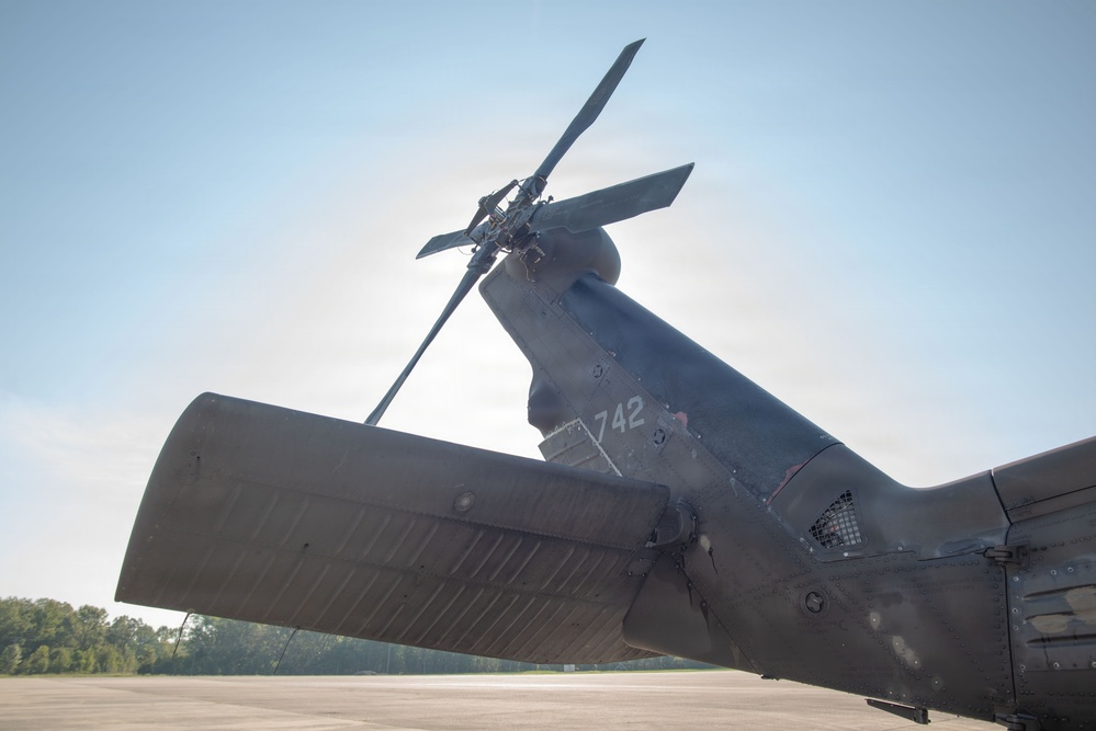 Close-up low-angle photograph of the tail section of a military helicopter, showing the tail rotor assembly and horizontal stabilizer. The aircraft bears the number '742' stenciled on the tail boom. The helicopter appears to be parked on a tarmac or airfield, photographed against a partly cloudy sky.