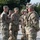 A senior U.S. Army officer wearing four-star general rank insignia is shaking hands with soldiers in a formal greeting or inspection ceremony. The general, whose name tape reads 'LANEYE' or similar, is accompanied by another high-ranking officer (visible two-star rank) as they move down a line of uniformed soldiers. The setting appears to be an outdoor military installation during daylight hours.