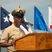 A U.S. Navy senior enlisted officer is speaking at a podium labeled 'Tactical Training Group Pacific,' likely during an official military ceremony. He is wearing the Navy Service Uniform (tan/khaki) with a combination cover bearing a senior chief or master chief insignia. Multiple state and organizational flags are displayed in the background.