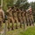 WWII Reenactors Deliver a 21 Gun Salute at the LT John S Thompson Bridge Ceremony, Operation Market Garden Commemorations 2026 A group of re-enactors dressed in WWII-era U.S. Army uniforms are performing a ceremonial rifle salute (volley fire) at what appears to be a commemorative event. The soldiers are lined up in formation, firing rifles skyward, while spectators and photographers observe from the background. A U.S. flag patch and period-accurate equipment suggest this is a memorial or historical re-enactment ceremony.