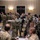 Space Force Connection Time at AFA 2026 A large group of military personnel in camouflage uniforms are gathered in what appears to be a hotel ballroom or conference facility. The gathering appears to be a military conference or networking event, with personnel mingling, conversing in small groups, and some holding beverages. A small number of civilians in business attire are also present among the uniformed attendees.