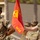 Two U.S. Marines in MARPAT woodland camouflage uniforms stand at attention during a formal military ceremony. One Marine holds a red guidon flag bearing the Eagle, Globe, and Anchor emblem with the designation 'GS CO' (General Support Company). Additional Marines are visible in the background, suggesting a unit formation or parade.