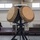 The image shows a military or tactical radar/antenna system mounted on a black tripod stand inside an indoor facility, likely a hangar or training hall. The system features two large circular phased-array antenna dishes in a tan/desert color scheme, with a 'Hemisphere' branded GPS/navigation unit mounted on top. Various control boxes, cables, and a cable reel are visible as part of the integrated system.