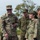 The image shows a group of military personnel from two different armed forces interacting in an outdoor setting. A U.S. Army soldier, identified by name tape 'MATBUYA' and U.S. Army insignia, is smiling and conversing with what appear to be Japan Ground Self-Defense Force (JGSDF) soldiers. The interaction appears friendly and relaxed, suggesting a joint training exercise or bilateral military engagement.