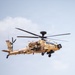A military attack helicopter is captured in flight against a light blue sky with partial cloud cover. The aircraft displays desert camouflage livery in tan and brown tones, with visible Indian Army markings including the Indian tricolor roundel and the word 'ARMY' on the fuselage. The helicopter appears to be an AH-64 Apache variant operated by the Indian Army.