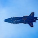 Two U.S. Navy Blue Angels F/A-18 Hornet jets are captured in extremely close formation flight against a blue sky. The aircraft are numbered 5 and 6, flying in an inverted mirror formation with their undersides nearly touching. The image showcases the precision flying characteristic of the Blue Angels flight demonstration squadron.