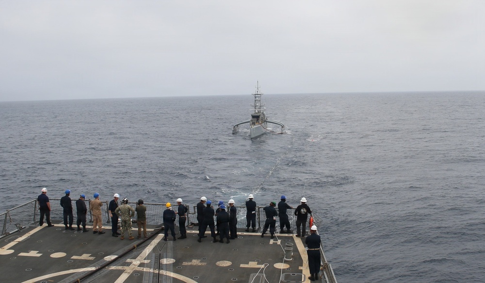 Apoio logístico ao Seahawk Militares no convés do USS Chafee acompanham o Seahawk durante abastecimento no mar.