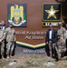 A group of military personnel and civilians pose for a formal photograph in front of the Mihail Kogălniceanu Air Base Main Gate sign in Romania. The sign displays both the Romanian military coat of arms and the U.S. Army logo, indicating a joint or bilateral military presence. The setting appears to be an official visit or ceremony at the base entrance.