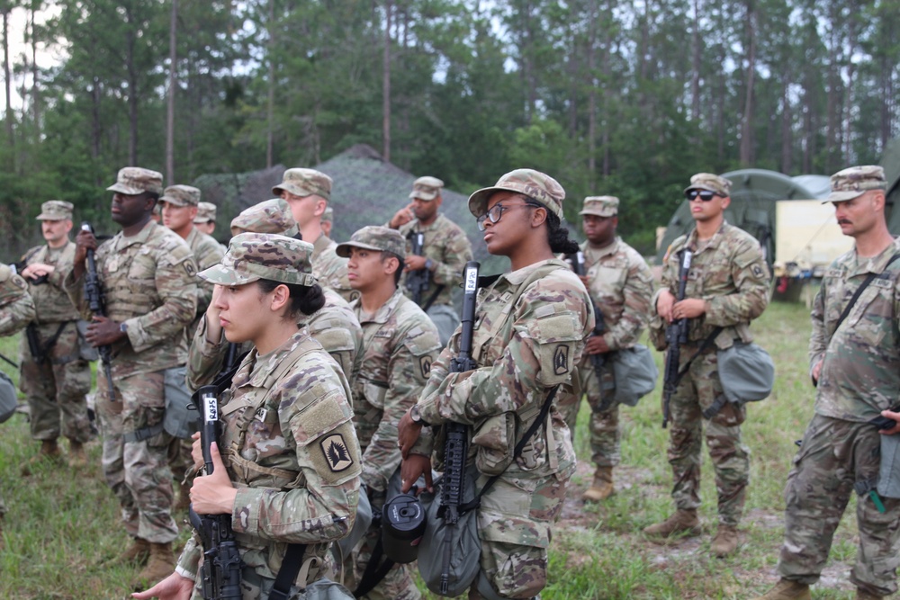 U.S. Army soldiers stand in formation during field training exercise at wooded base camp