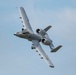 A Fairchild Republic A-10 Thunderbolt II (commonly known as the 'Warthog') is captured in flight against a partly cloudy blue sky. The aircraft is banked at a steep angle, providing a clear view of its distinctive twin turbofan engines mounted above the rear fuselage, straight wings, and characteristic shark mouth nose art. The image is sharp and well-exposed, typical of an airshow or training flight photograph.