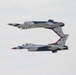 Two United States Air Force Thunderbirds F-16 Fighting Falcon jets are performing a mirror pass maneuver, with one aircraft flying inverted directly above the other. The jets display the iconic Thunderbirds red, white, and blue livery with star markings on the tail fins. The aircraft are numbered 5 and 6, indicating they are the solo demonstration pilots of the team.